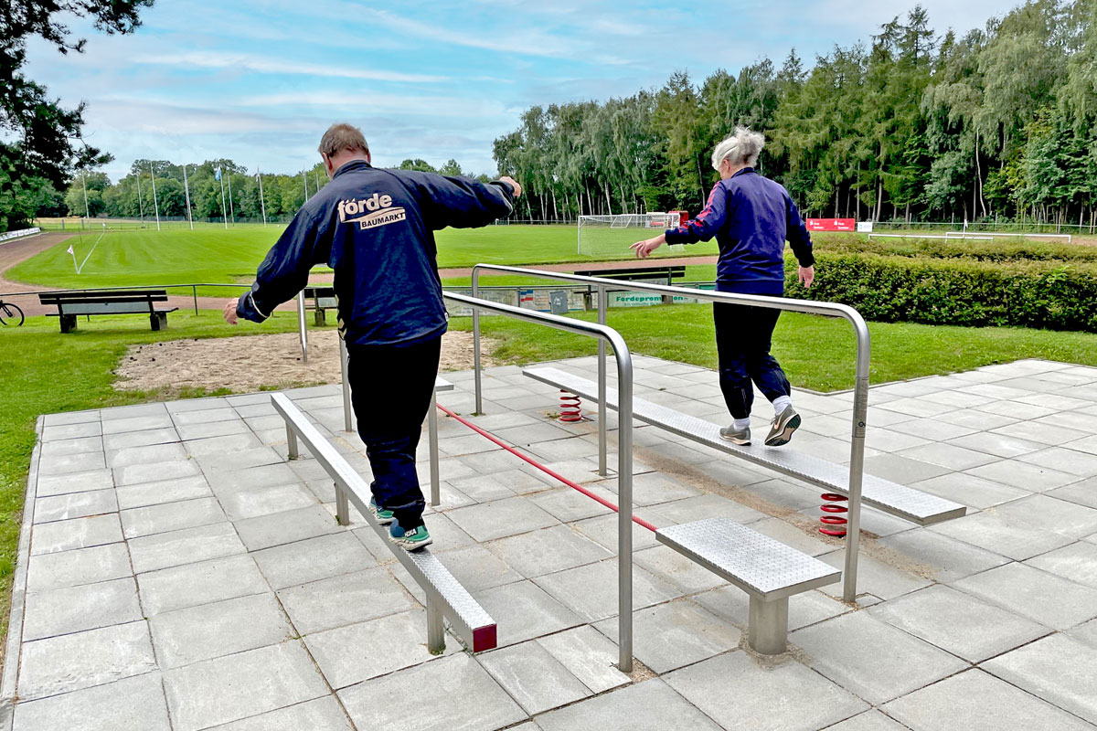 Zwei Menschen balancieren auf der Balancierstrecke im Outdoor-Bereich